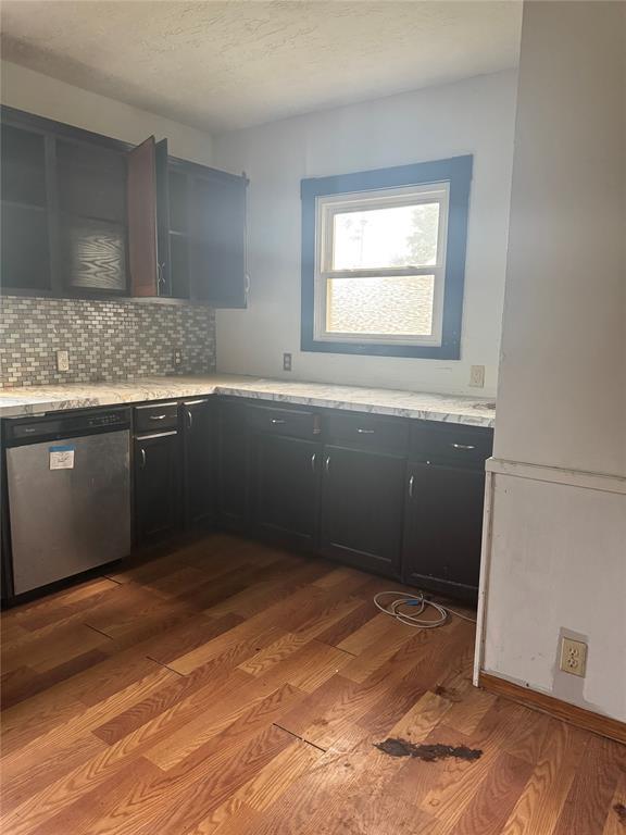 201 S Oak St, Pauls Valley, OK 73075 - kitchen with dishwasher, light wood-style floors, dark cabinetry, and backsplash