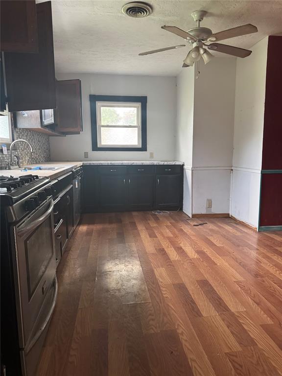 201 S Oak St, Pauls Valley, OK 73075 - kitchen featuring stainless steel gas range oven, wood finished floors, ceiling fan, light countertops, and backsplash