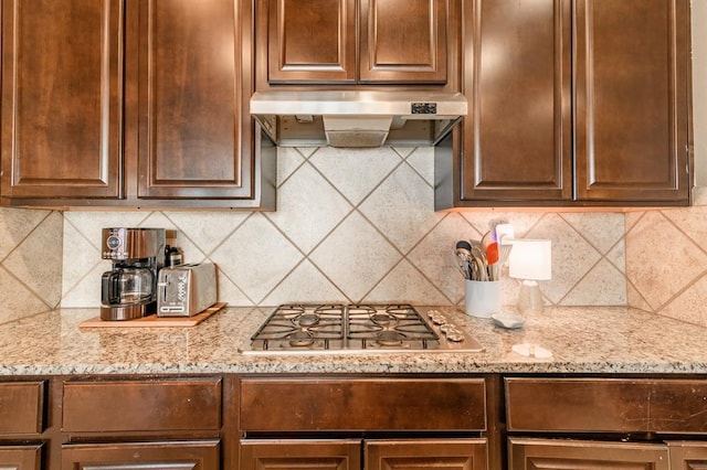 3101 Firewheel Rd, Edmond, OK 73013 - kitchen featuring under cabinet range hood, stainless steel gas stovetop, light stone countertops, and backsplash