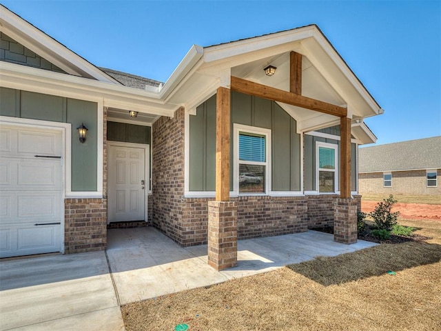 13172 Mannington Rd, Edmond, OK 73025 - doorway to property featuring board and batten siding, a garage, and brick siding
