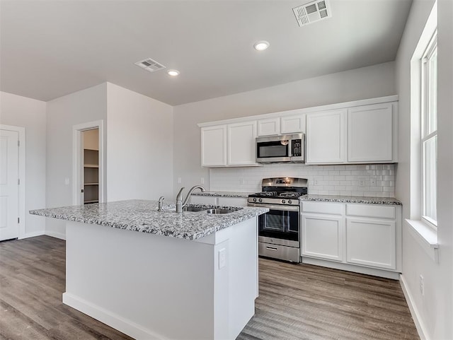 13172 Mannington Rd, Edmond, OK 73025 - kitchen featuring appliances with stainless steel finishes, wood finished floors, backsplash, white cabinetry, and light stone countertops