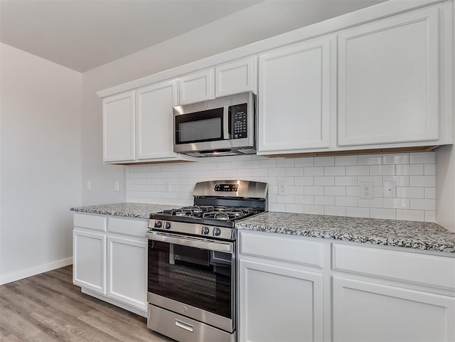 13172 Mannington Rd, Edmond, OK 73025 - kitchen featuring appliances with stainless steel finishes, light stone countertops, light wood-type flooring, white cabinetry, and tasteful backsplash