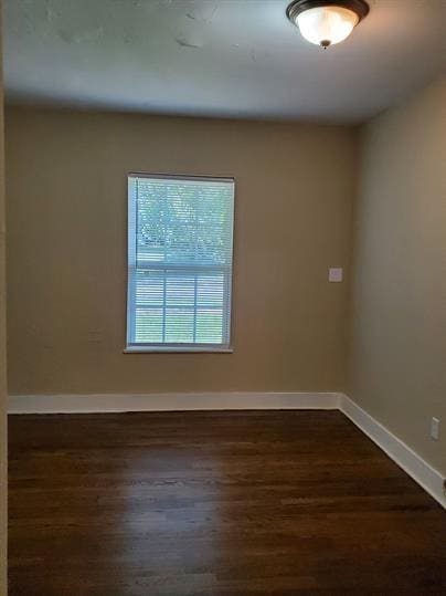 unfurnished room with dark wood finished floors and baseboards