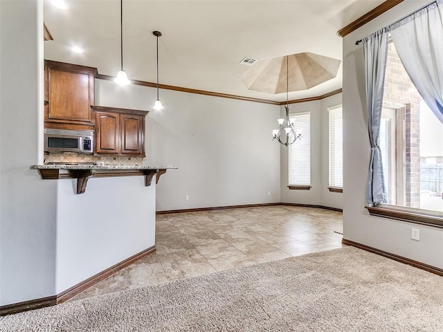 12824 NW 6th St, Yukon, OK 73099 - kitchen featuring stainless steel microwave, a kitchen breakfast bar, decorative backsplash, decorative light fixtures, and a chandelier