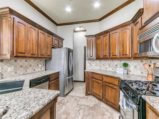 12824 NW 6th St, Yukon, OK 73099 - kitchen with stainless steel appliances, light stone counters, backsplash, crown molding, and brown cabinetry