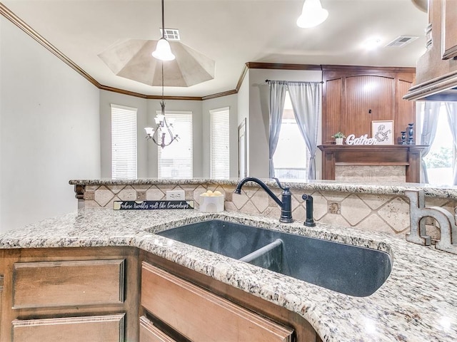 12824 NW 6th St, Yukon, OK 73099 - kitchen with crown molding, a chandelier, light stone counters, and pendant lighting