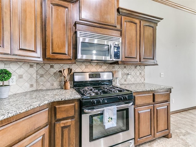 12824 NW 6th St, Yukon, OK 73099 - kitchen with stainless steel appliances, light stone counters, backsplash, and brown cabinets