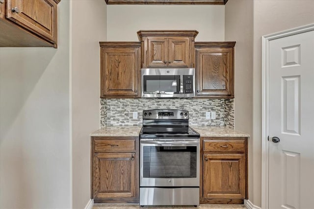 600 Nathan Way, Yukon, OK 73099 - kitchen with appliances with stainless steel finishes, backsplash, brown cabinets, and light stone counters