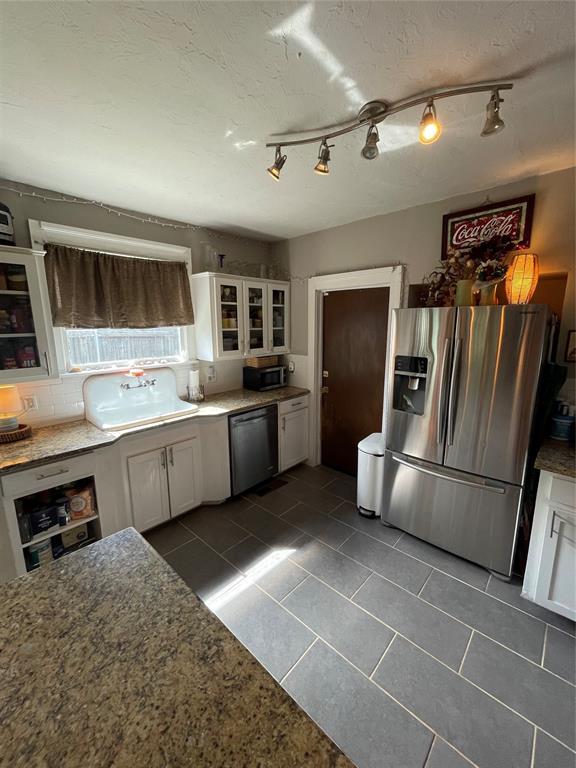 1845 W Park Pl, Oklahoma City, OK 73106 - kitchen with appliances with stainless steel finishes, white cabinetry, track lighting, glass insert cabinets, and a textured ceiling