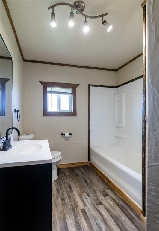 22807 E 1070th Rd, Clinton, OK 73601 - bathroom with vanity, ornamental molding, wood finished floors, and shower / bathtub combination