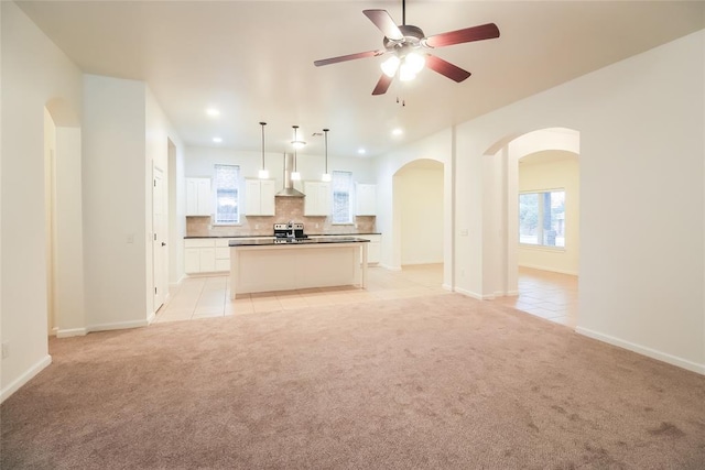 10928 NW 38th Ter, Yukon, OK 73099 - kitchen featuring wall chimney range hood, open floor plan, light carpet, light tile patterned floors, and stainless steel electric stove