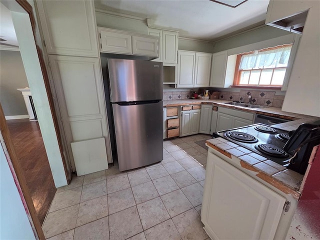 1103 S Hadden Ave, El Reno, OK 73036 - kitchen with freestanding refrigerator, tile countertops, ornamental molding, backsplash, and white cabinetry