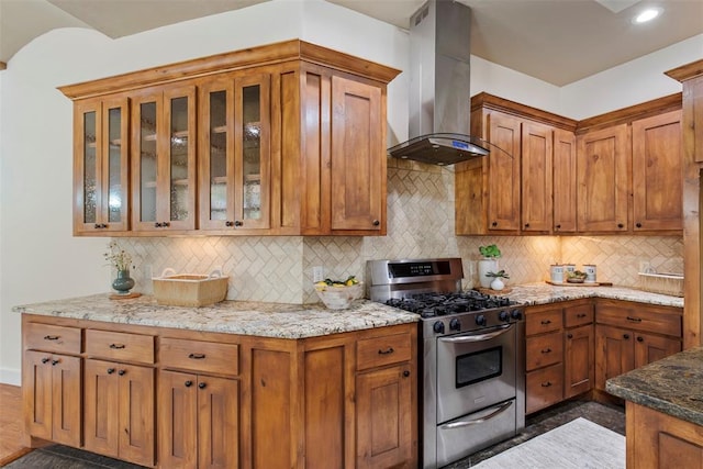 15016 Kurdson Way, Edmond, OK 73013 - kitchen with stainless steel gas stove, island range hood, light stone counters, decorative backsplash, and glass insert cabinets