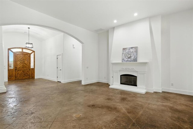 15016 Kurdson Way, Edmond, OK 73013 - unfurnished living room with arched walkways, recessed lighting, and a glass covered fireplace