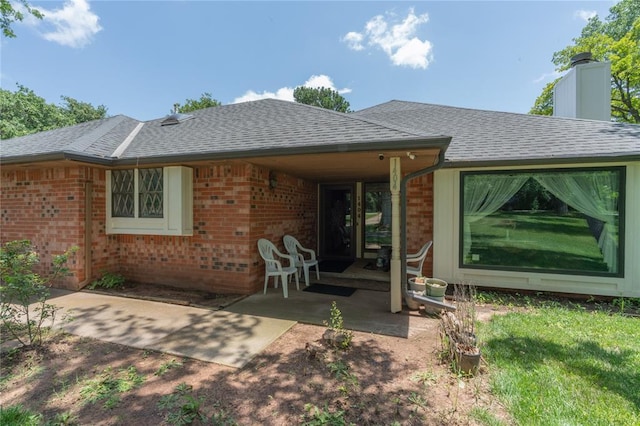 1404 Oak Dr, Edmond, OK 73034 - rear view of property featuring brick siding, roof with shingles, a patio, and a chimney