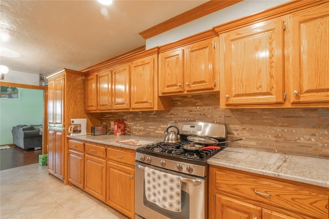 1404 Oak Dr, Edmond, OK 73034 - kitchen featuring stainless steel range with gas cooktop, light countertops, decorative backsplash, and light tile patterned flooring