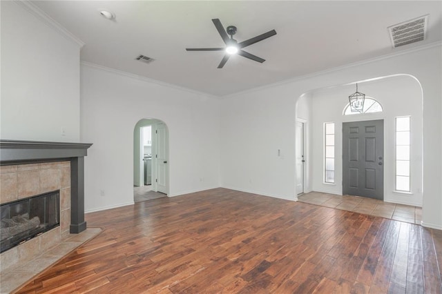 201 NW 160th Ter, Edmond, OK 73013 - unfurnished living room featuring arched walkways, a ceiling fan, hardwood / wood-style flooring, crown molding, and a fireplace
