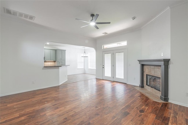 201 NW 160th Ter, Edmond, OK 73013 - unfurnished living room featuring a tiled fireplace, crown molding, ceiling fan, and wood finished floors