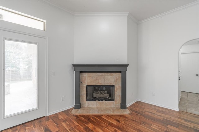 201 NW 160th Ter, Edmond, OK 73013 - unfurnished living room featuring ornamental molding, wood finished floors, a fireplace, and arched walkways