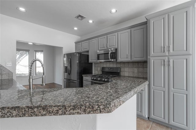 201 NW 160th Ter, Edmond, OK 73013 - kitchen featuring appliances with stainless steel finishes, gray cabinets, recessed lighting, backsplash, and a peninsula