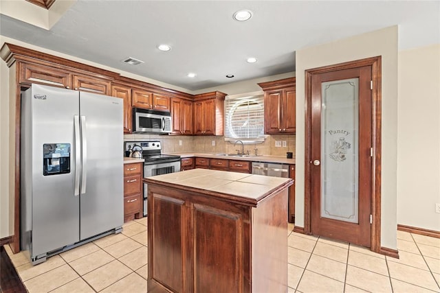 4705 Stag Horn Dr, Yukon, OK 73099 - kitchen featuring stainless steel appliances, light tile patterned flooring, tasteful backsplash, a kitchen island, and recessed lighting