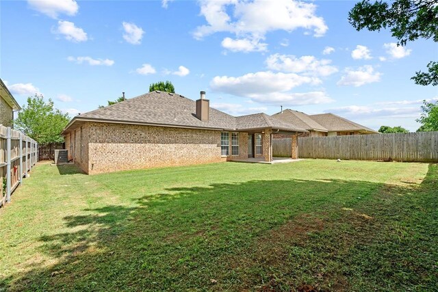 4705 Stag Horn Dr, Yukon, OK 73099 - back of house with brick siding, a fenced backyard, a patio area, a chimney, and a shingled roof