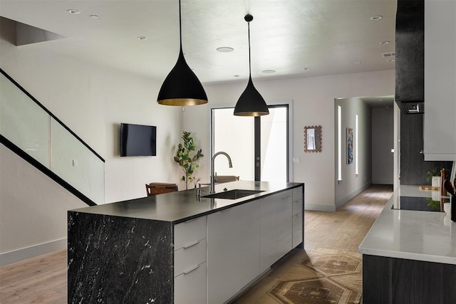 907 NW 9th St Unit B, Oklahoma City, OK 73106 - kitchen featuring light wood-style floors, modern cabinets, a center island with sink, pendant lighting, and black electric cooktop