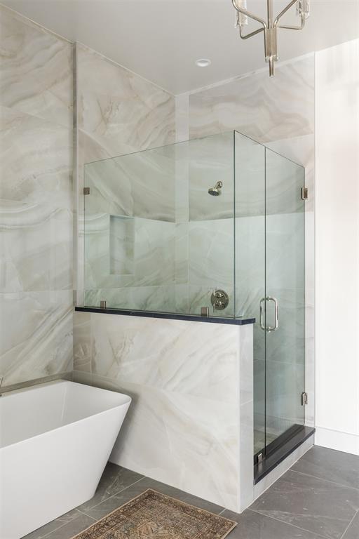 907 NW 9th St Unit B, Oklahoma City, OK 73106 - bathroom with marble look tile flooring, a freestanding bath, a stall shower, and a chandelier