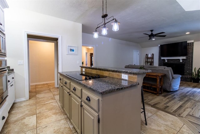 10517 SE 49th St, Oklahoma City, OK 73150 - kitchen featuring black electric cooktop, a kitchen bar, a kitchen island, ceiling fan, and pendant lighting