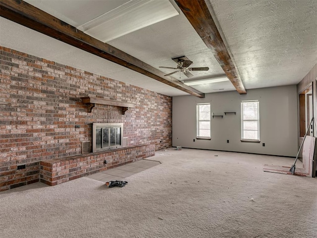 356818 E 1070th Rd, Prague, OK 74864 - unfurnished living room with a brick fireplace, a ceiling fan, a textured ceiling, carpet floors, and beamed ceiling