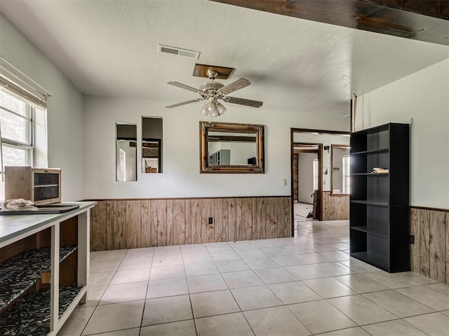 356818 E 1070th Rd, Prague, OK 74864 - unfurnished dining area with wainscoting, wooden walls, a ceiling fan, and light tile patterned flooring