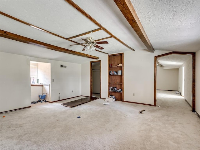 356818 E 1070th Rd, Prague, OK 74864 - unfurnished living room featuring beam ceiling, a textured ceiling, ceiling fan, and carpet floors