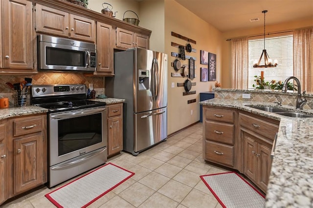 2704 Jills Trl, Edmond, OK 73012 - kitchen with appliances with stainless steel finishes, tasteful backsplash, light tile patterned floors, decorative light fixtures, and light stone counters