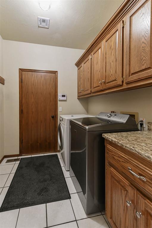 2704 Jills Trl, Edmond, OK 73012 - washroom featuring cabinet space, washing machine and clothes dryer, and light tile patterned flooring