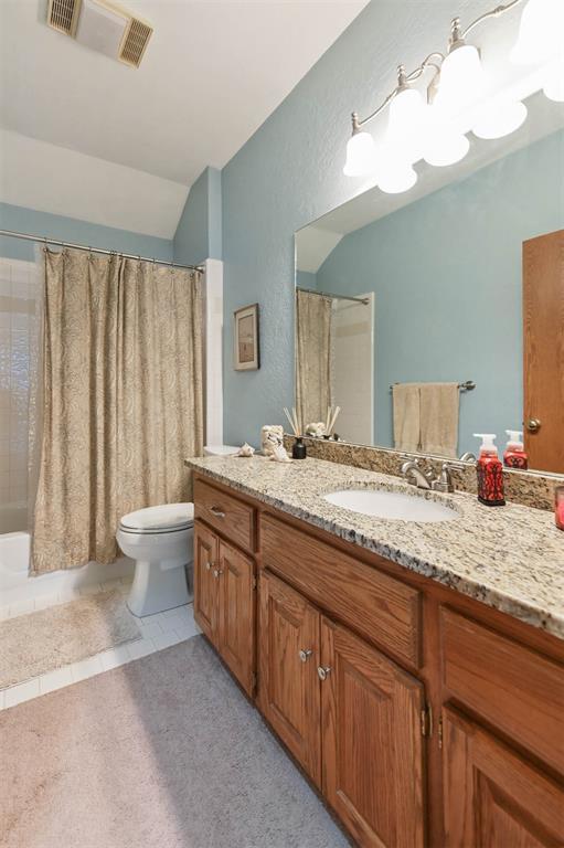 2704 Jills Trl, Edmond, OK 73012 - bathroom with vanity, shower / bath combo with shower curtain, lofted ceiling, and a textured wall
