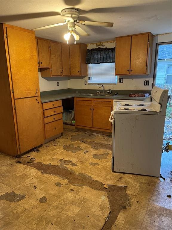 1309 W Pecan Ave, Duncan, OK 73533 - kitchen with white electric range oven, brown cabinetry, dark countertops, and a ceiling fan