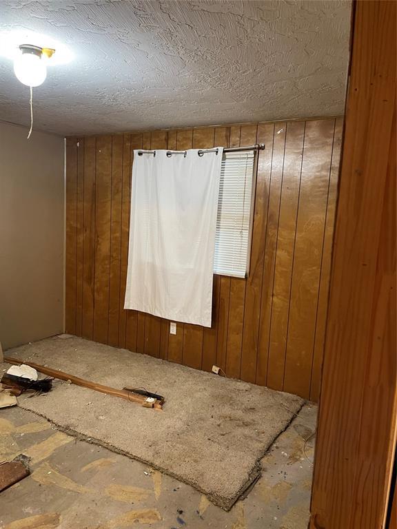 1309 W Pecan Ave, Duncan, OK 73533 - unfurnished room featuring wooden walls and a textured ceiling