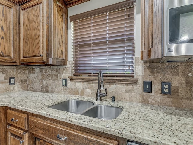 11749 SW 16th St, Yukon, OK 73099 - kitchen featuring stainless steel microwave, brown cabinetry, backsplash, and light stone countertops