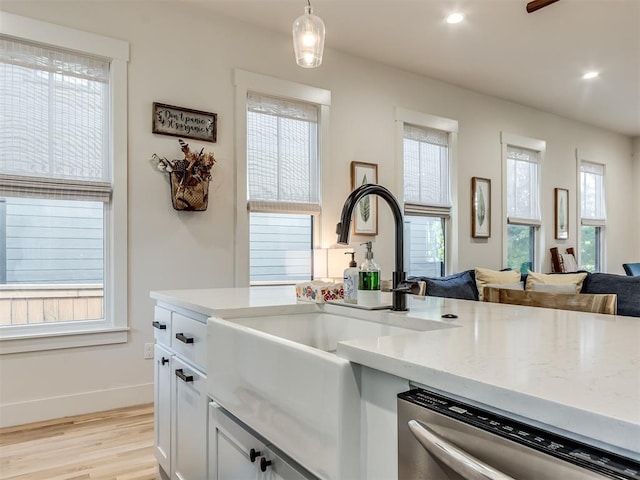 75 Lower Green Way, Carlton Landing, OK 74432 - kitchen featuring stainless steel dishwasher, light wood finished floors, open floor plan, decorative light fixtures, and white cabinetry