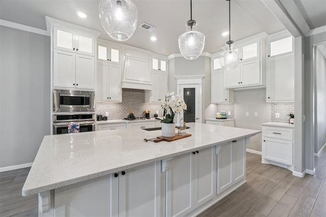12904 SW 8th St, Yukon, OK 73099 - kitchen with stainless steel appliances, white cabinets, a large island, tasteful backsplash, and light wood-style flooring