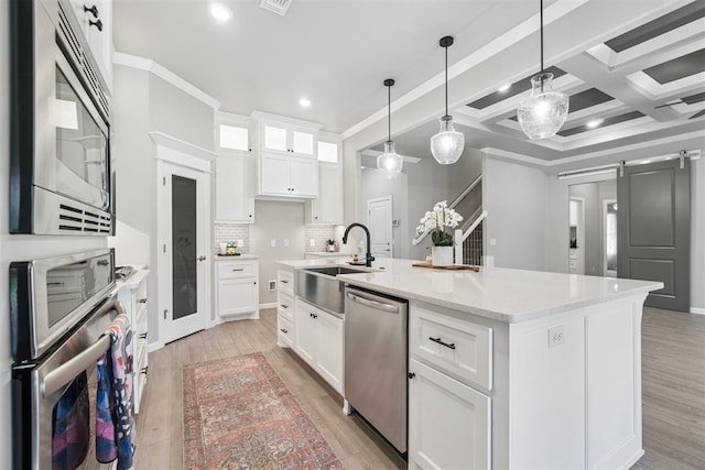12904 SW 8th St, Yukon, OK 73099 - kitchen featuring stainless steel appliances, a center island with sink, a barn door, tasteful backsplash, and white cabinets
