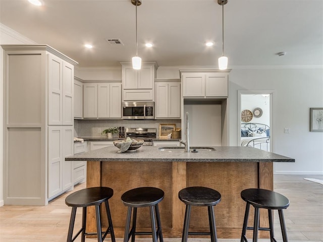 11728 SW 14th St, Yukon, OK 73099 - kitchen featuring stainless steel appliances, ornamental molding, a breakfast bar, light wood finished floors, and a center island with sink