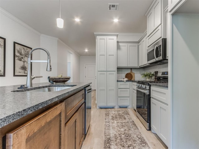 11728 SW 14th St, Yukon, OK 73099 - kitchen featuring stainless steel appliances, dark countertops, crown molding, light wood-style floors, and recessed lighting