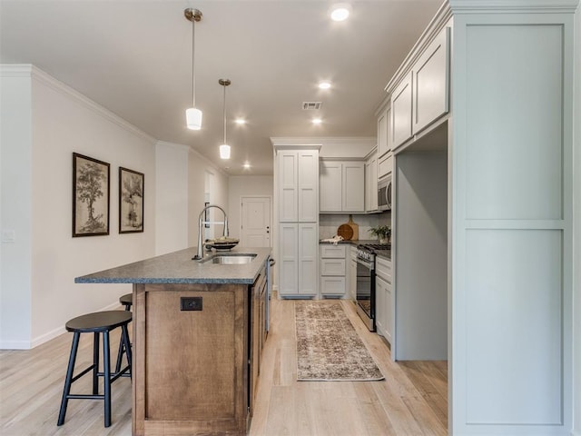 11728 SW 14th St, Yukon, OK 73099 - kitchen with stainless steel appliances, dark countertops, light wood-type flooring, a center island with sink, and crown molding