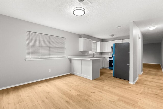 4800 SE 45th St, Oklahoma City, OK 73135 - kitchen with freestanding refrigerator, light countertops, a peninsula, light wood-style flooring, and stainless steel stove