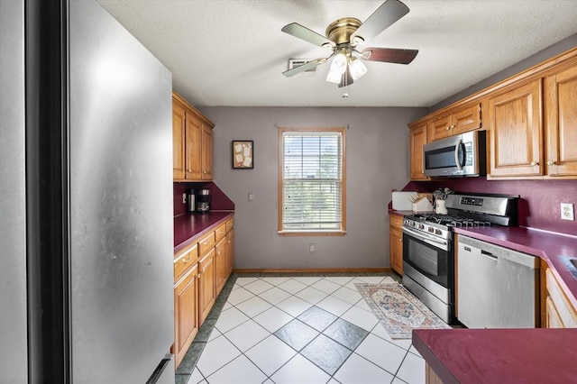 910796 S 3350th Rd, Wellston, OK 74881 - kitchen with appliances with stainless steel finishes, a ceiling fan, dark countertops, light tile patterned flooring, and a textured ceiling