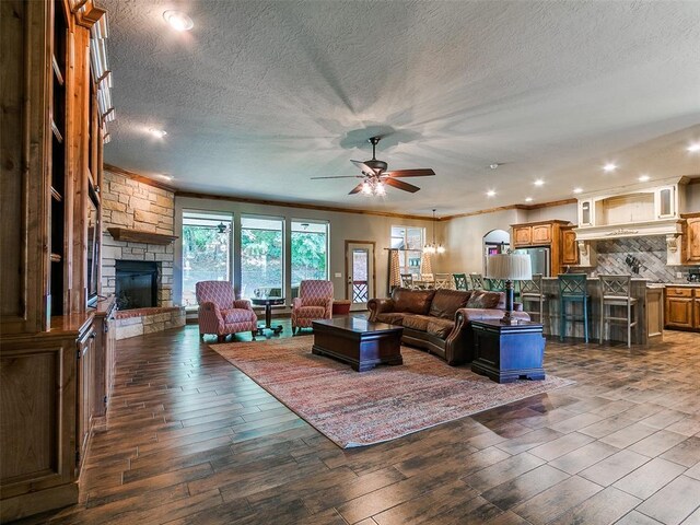 12905 S Mustang Rd, Mustang, OK 73064 - living area featuring a stone fireplace, a textured ceiling, ceiling fan, recessed lighting, and ornamental molding