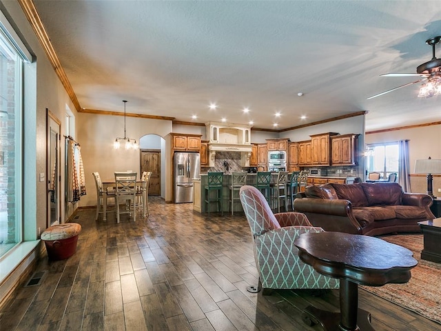 12905 S Mustang Rd, Mustang, OK 73064 - living room featuring crown molding, dark wood-style flooring, ceiling fan, and arched walkways