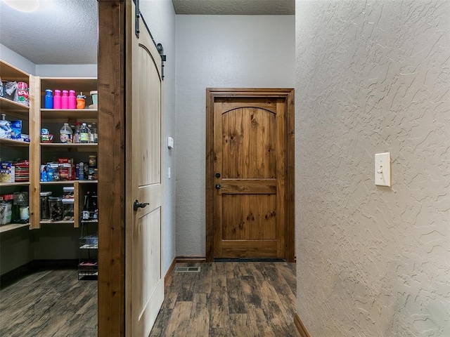 12905 S Mustang Rd, Mustang, OK 73064 - entryway with wood finished floors, a textured wall, a textured ceiling, and a barn door
