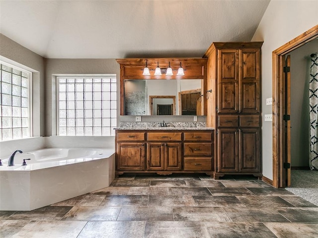 12905 S Mustang Rd, Mustang, OK 73064 - full bathroom with vanity, a garden tub, stone finish floors, and lofted ceiling